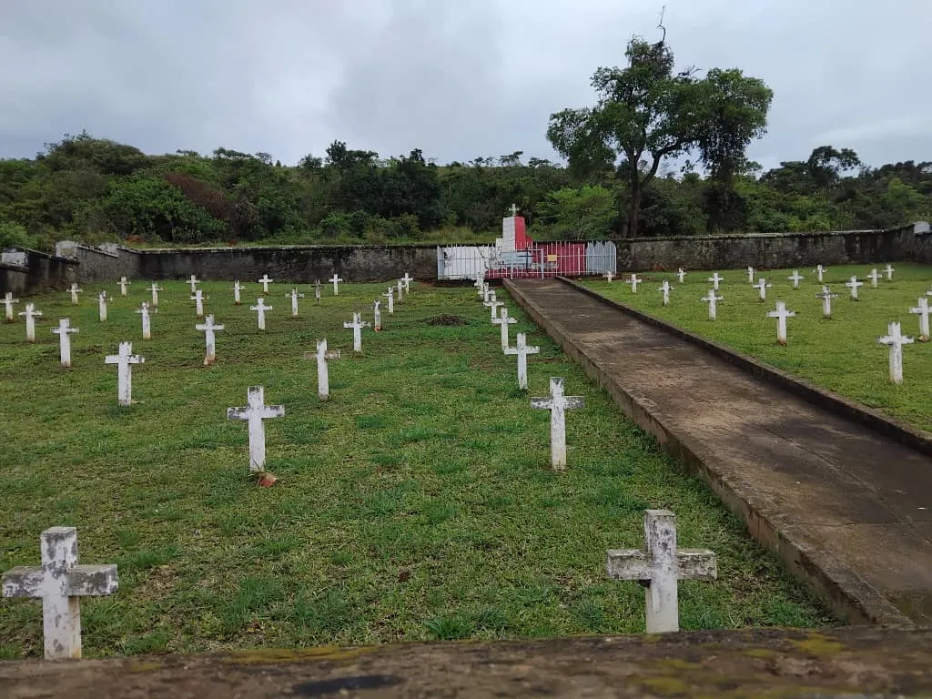 The Polish cemetery at Koja, Uganda, with rows of white crosses behind a low wall and a central memorial.